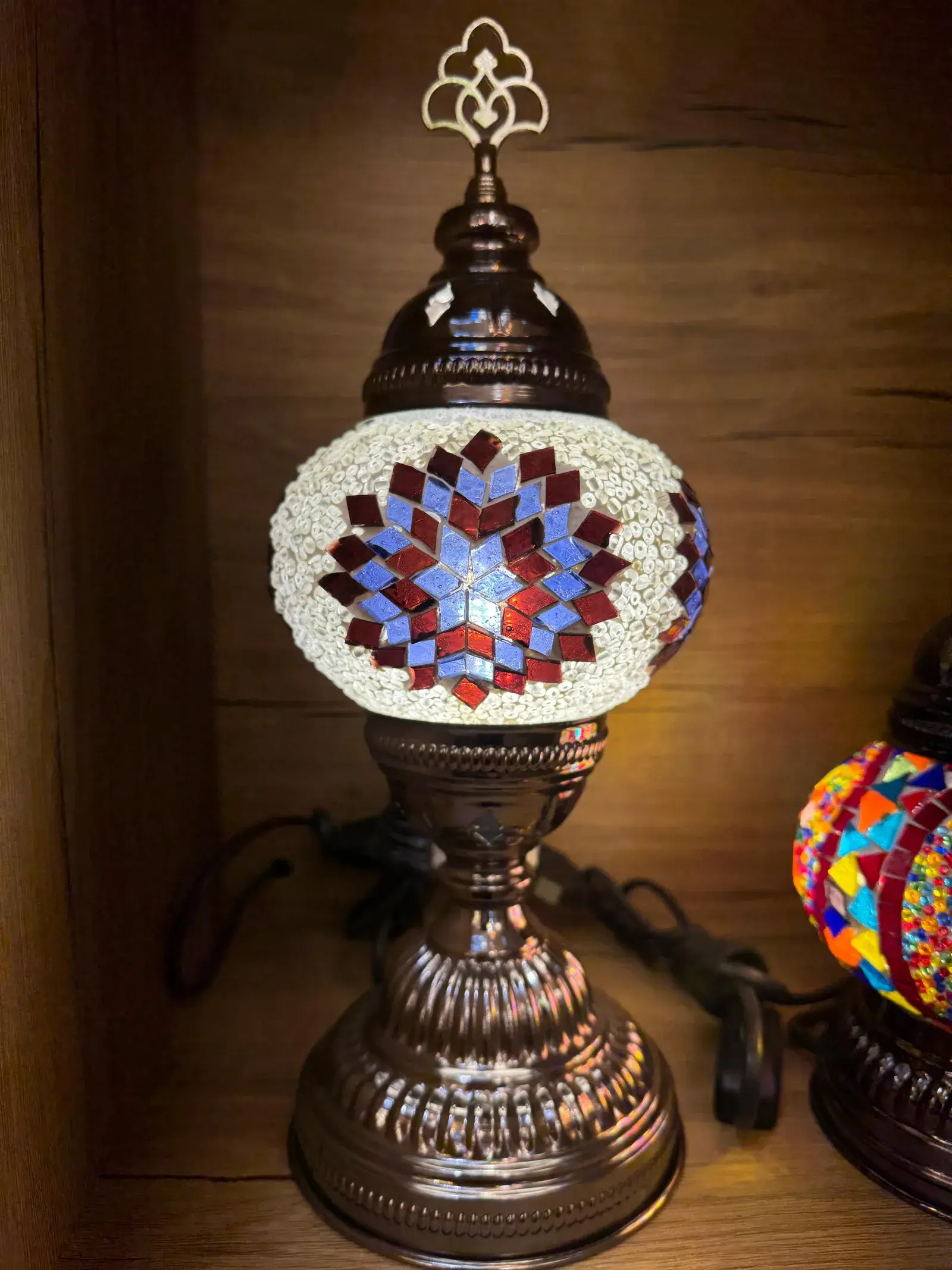 Amber and gold mosaic lamp glowing warm in our Balat workshop