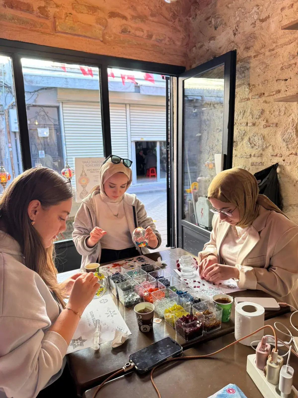 Pressing glass tesserae into place on a mosaic lamp in Balat