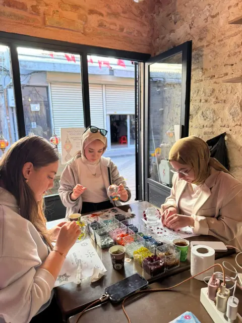 Three guests setting glass on their lamps at the window table